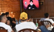 Viewers in Beirut watch Hezbollah leader Hassan Nasrallah's televised speech on Sunday evening (25 August). (© picture alliance / Anadolu / Houssam Shbaro)